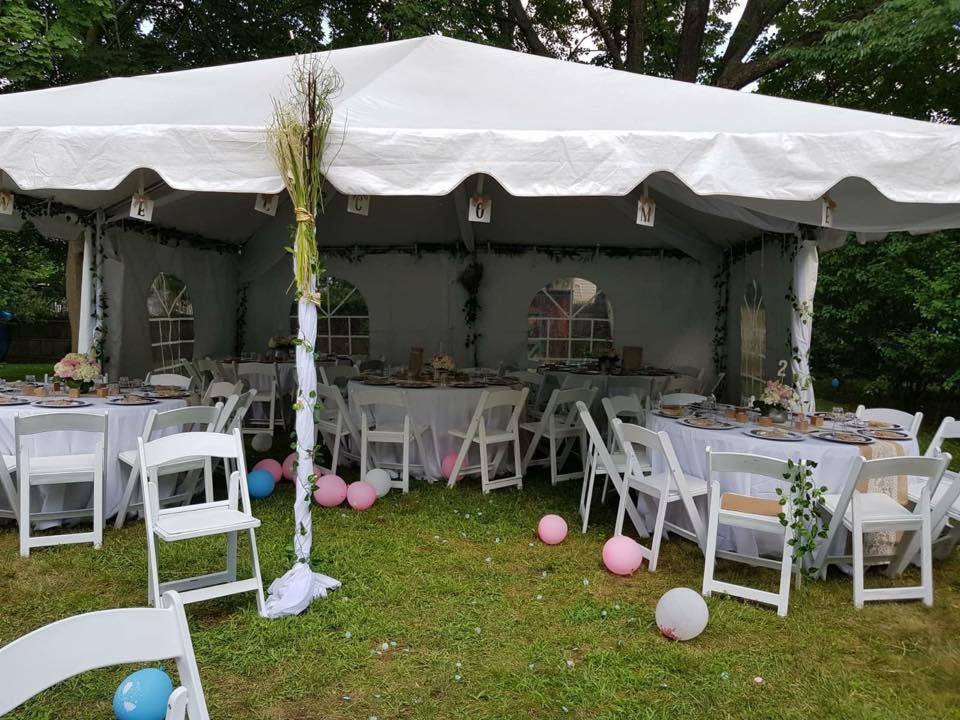 a white tent with tables and chairs in a grassy area