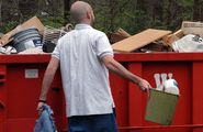 Man bringing trash to a dumpster