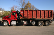 Truck delivering a roll-off dumpster