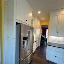 A kitchen with white cabinets and a stainless steel refrigerator.