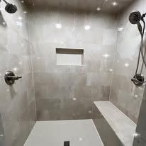 A shower with two shower heads and a bench.