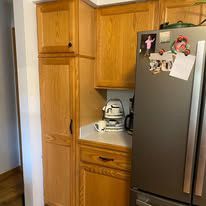 A kitchen with wooden cabinets and a stainless steel refrigerator.