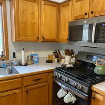 A kitchen with wooden cabinets , a stove , a sink , and a microwave.
