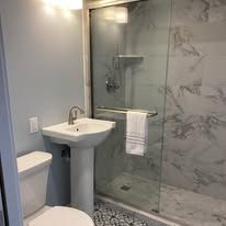 A bathroom with a toilet , sink , and walk in shower.