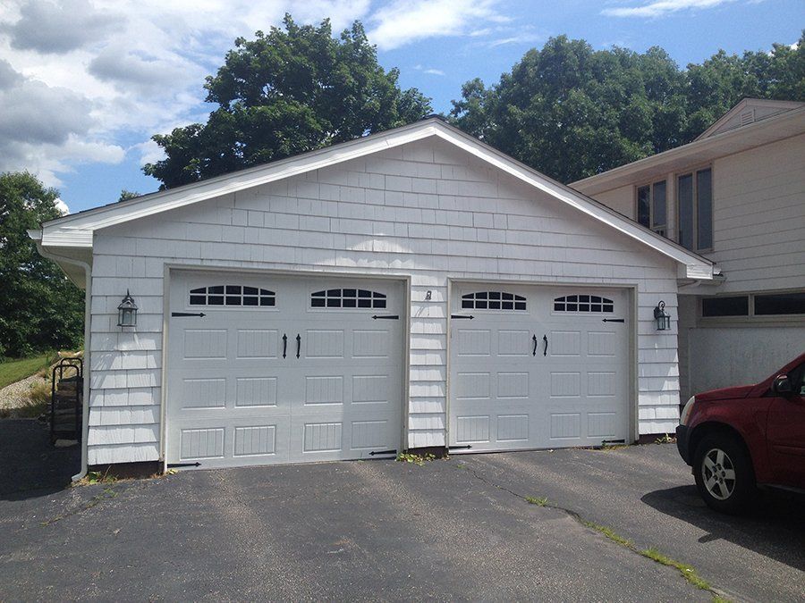 A red car is parked in front of a white garage
