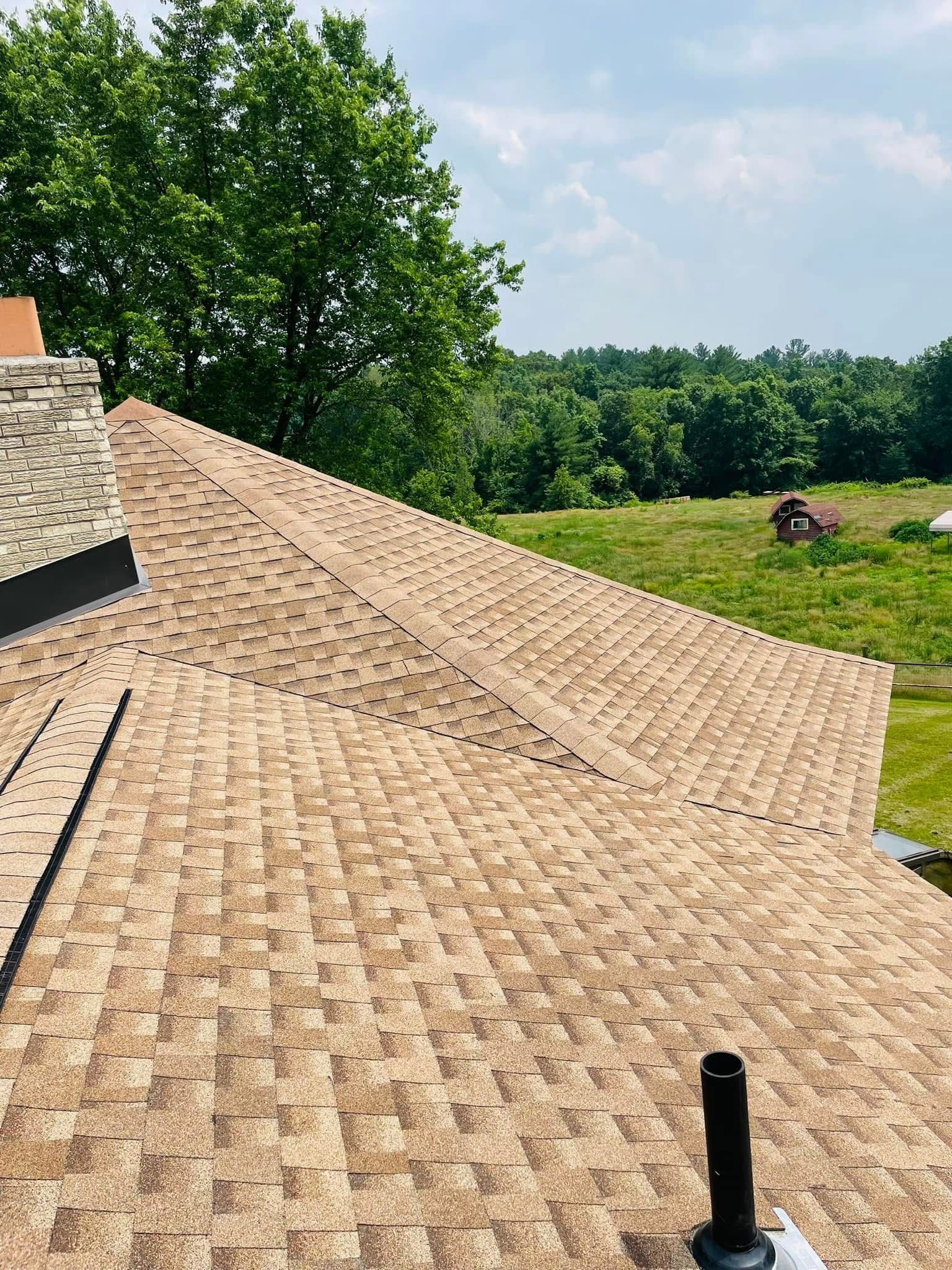 A roof with a chimney on it and a field in the background.
