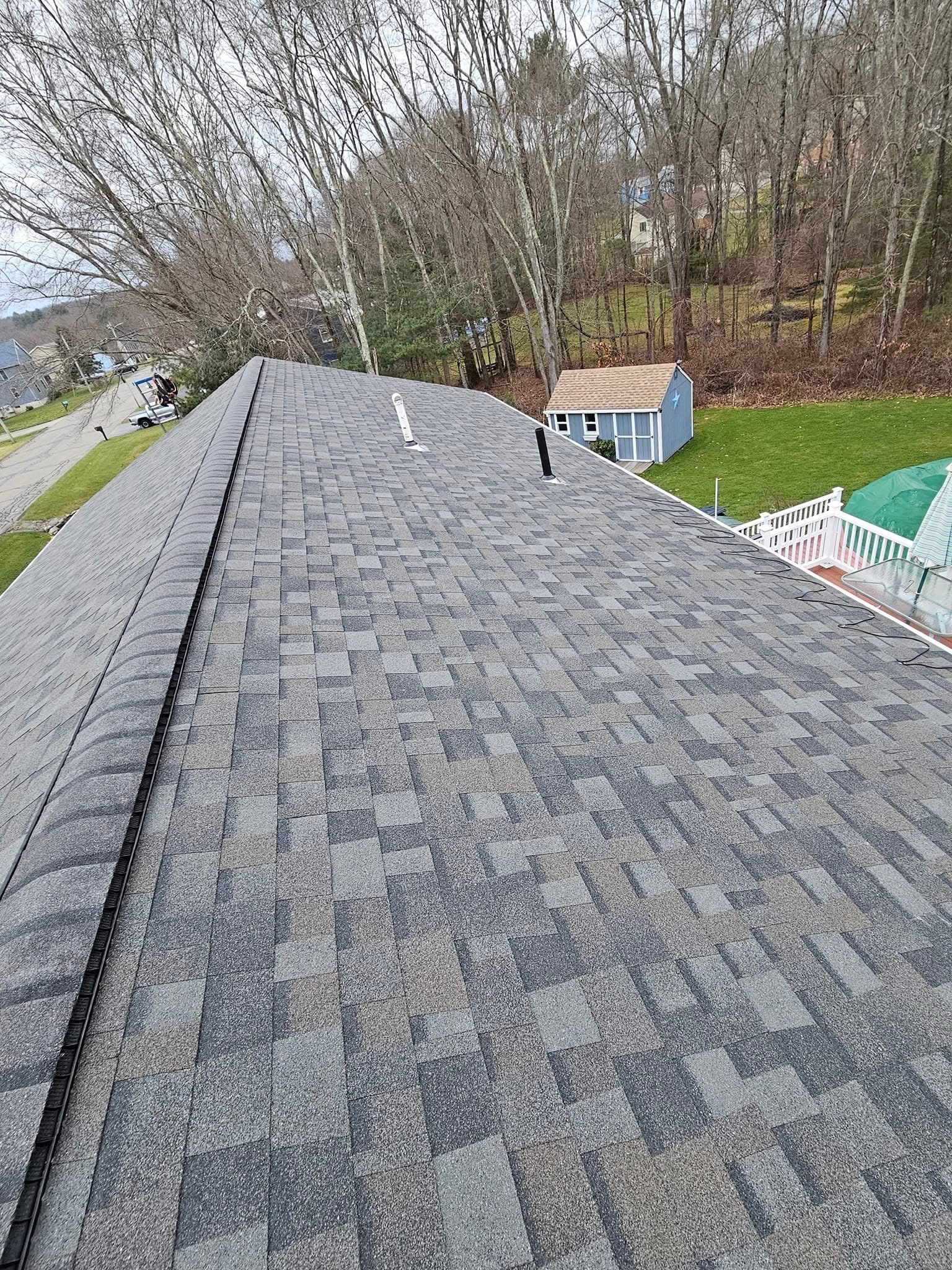 A close up of a roof with a shed in the background.