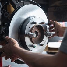 A man is fixing a brake disc on a car.