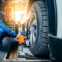 A man is adjusting a tire on a car in a garage.