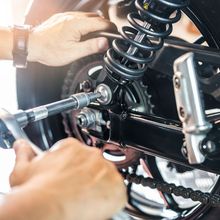 A person is working on a motorcycle with a wrench.