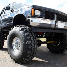 A black truck with big tires is parked on the road