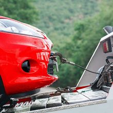 A red car is being towed by a tow truck.