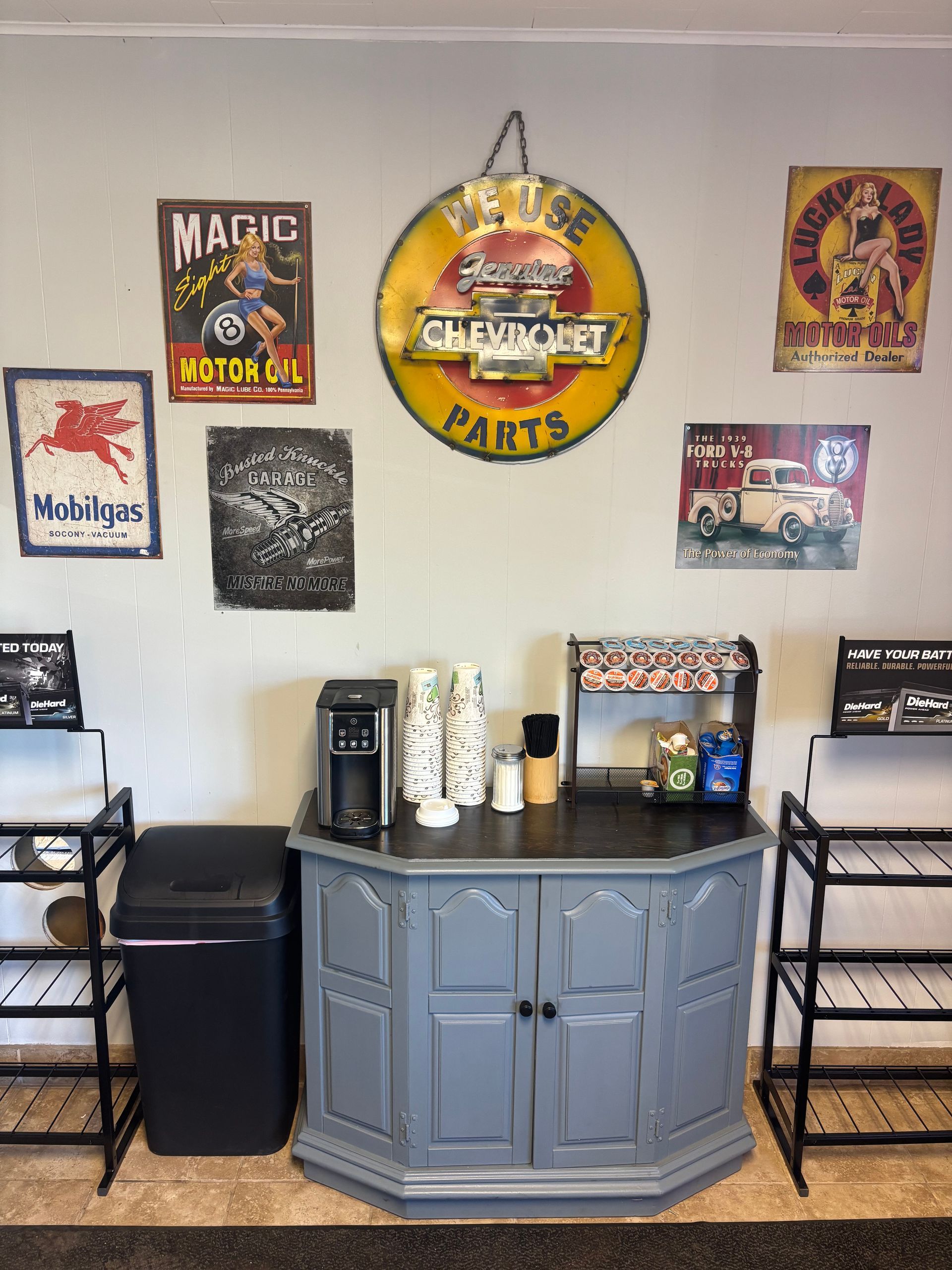 A coffee station in a garage with a chevrolet sign on the wall.
