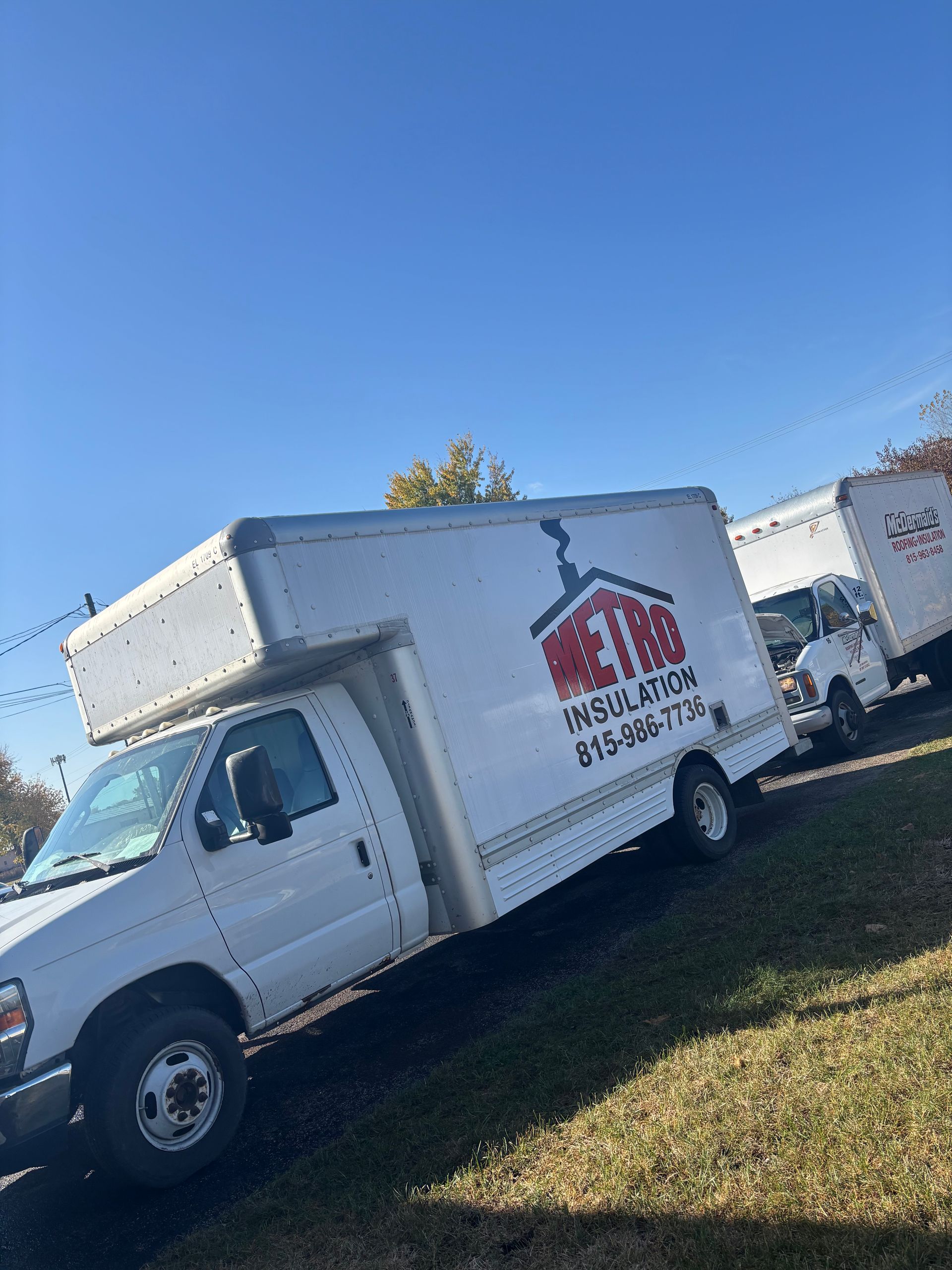 A white moving truck is parked in a grassy field.