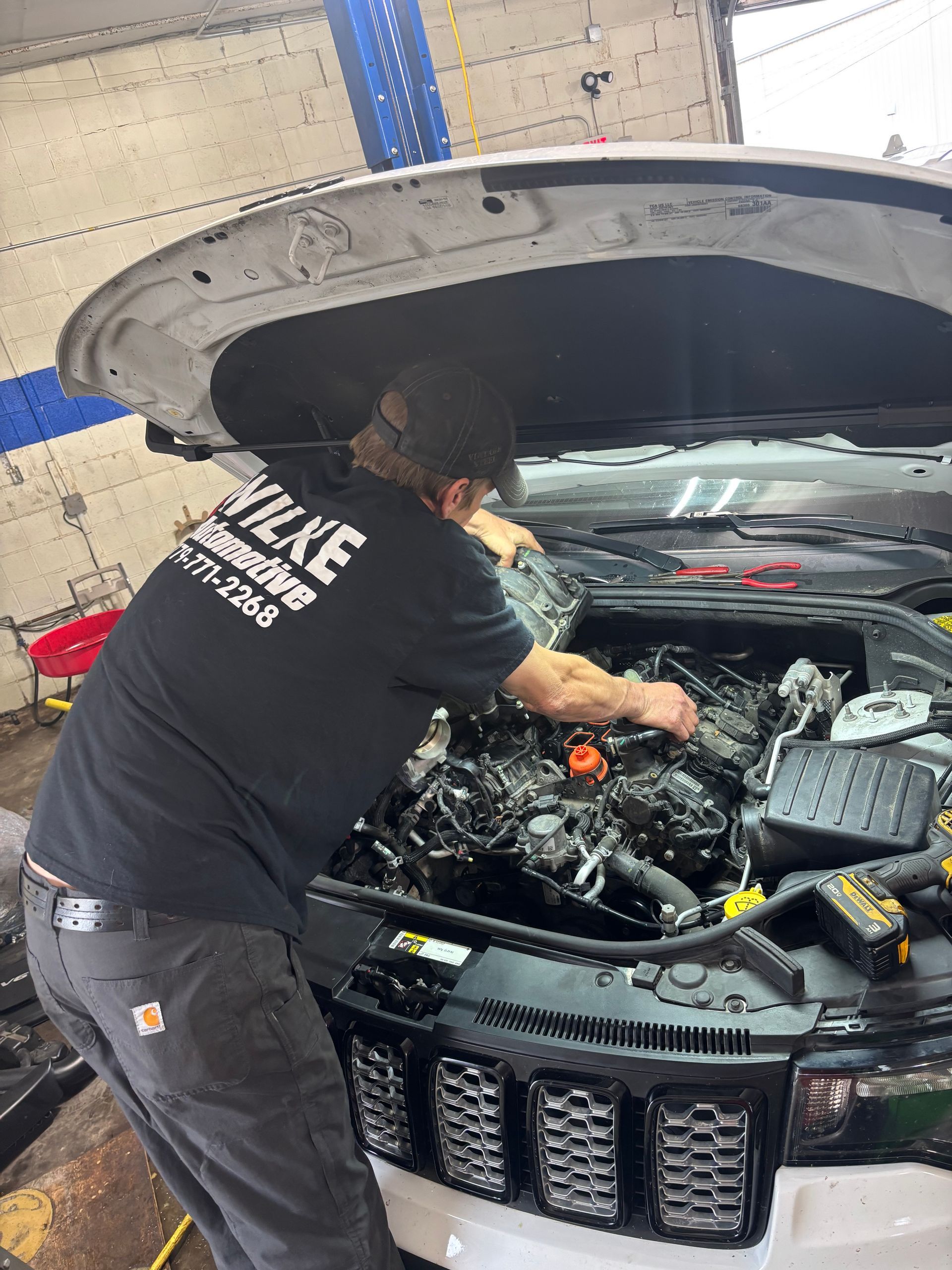 A man is working on the engine of a car in a garage.