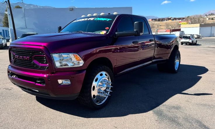Purple Ram 3500 dually truck parked outside on a sunny day. It has chrome wheels and a custom grill.