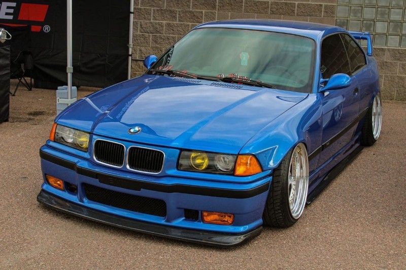 A blue bmw is parked in front of a brick building