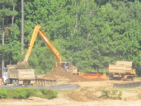 Backhoe dumping soil to dumptruck