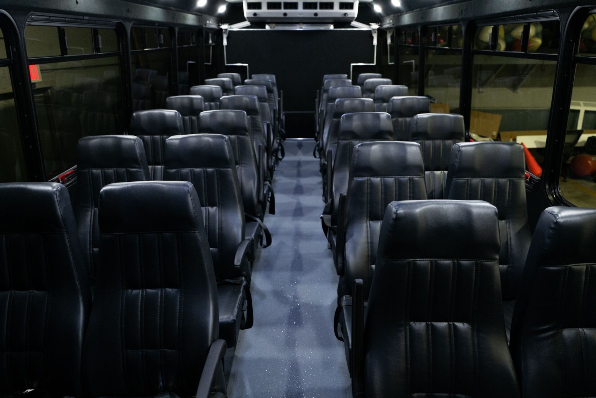 The inside of an empty bus with black seats.