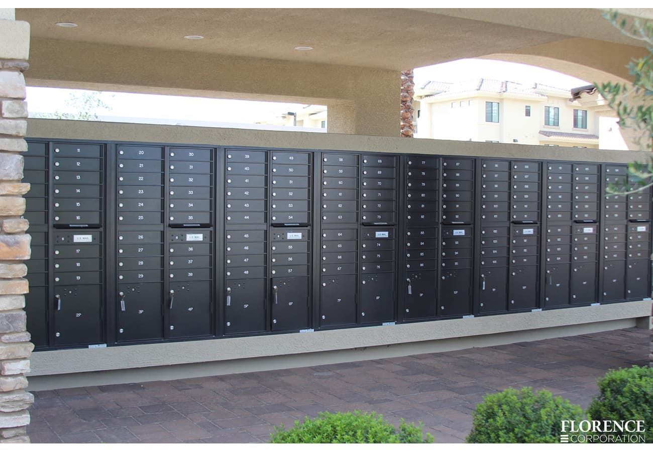 Row of black apartment mailboxes under an outdoor covered walkway.