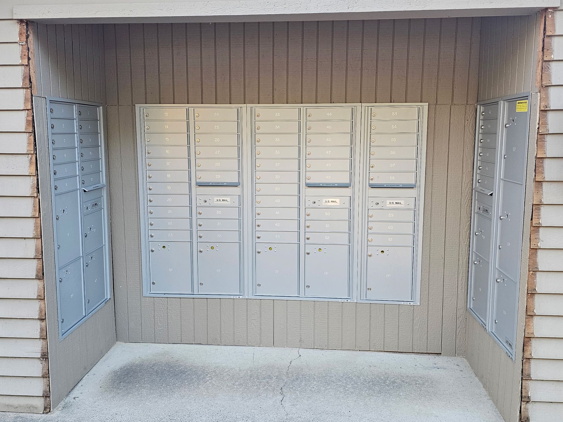 Mailboxes recessed in a wall nook, with white boxes centered between beige wood-paneled sides.
