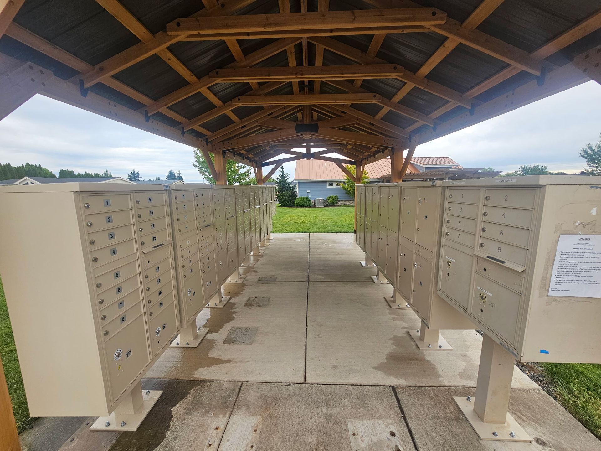Covered walkway with rows of beige mailboxes on both sides and a concrete path in the center.