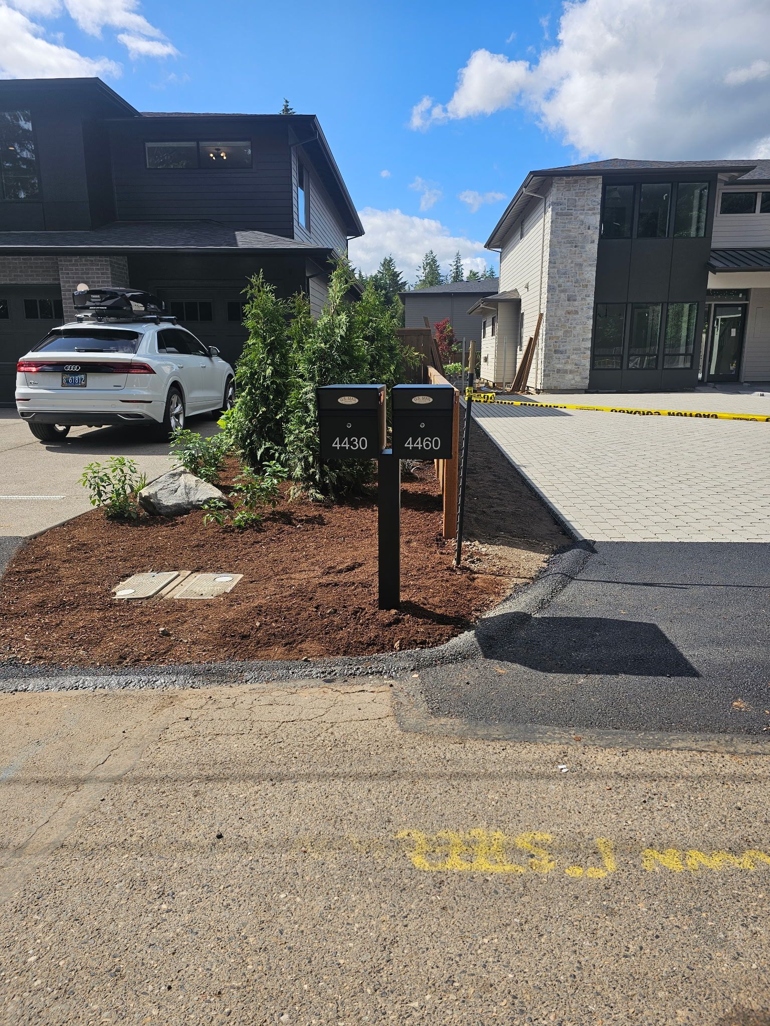 Apartment parking lot with a mailbox cluster, landscaped island, and parked cars under a blue sky