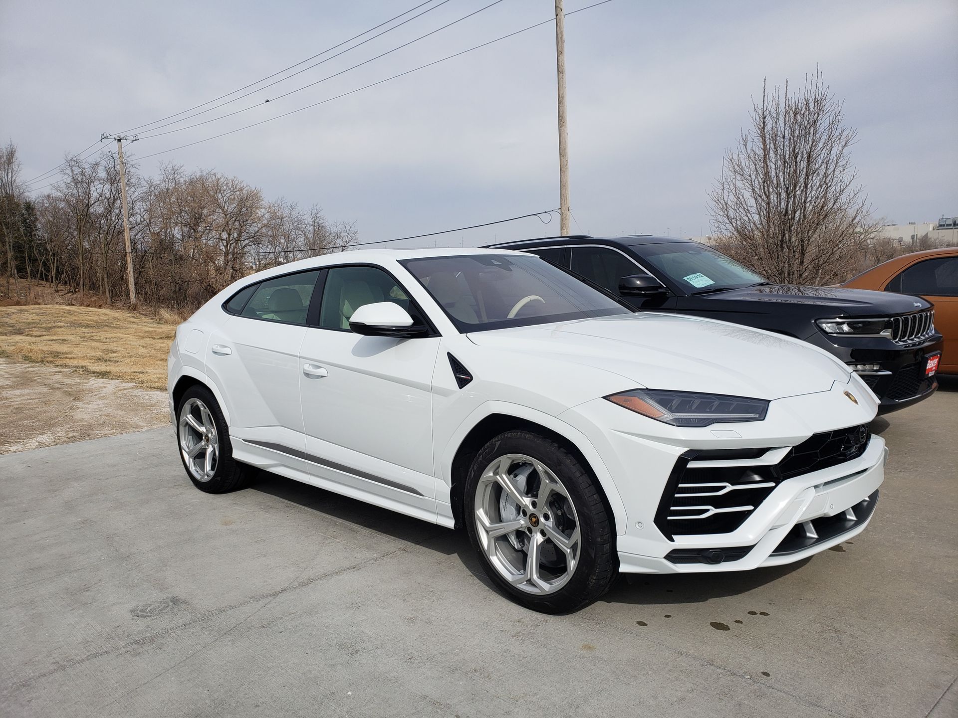 White Lamborghini Urus SUV parked outdoors on a sunny day.