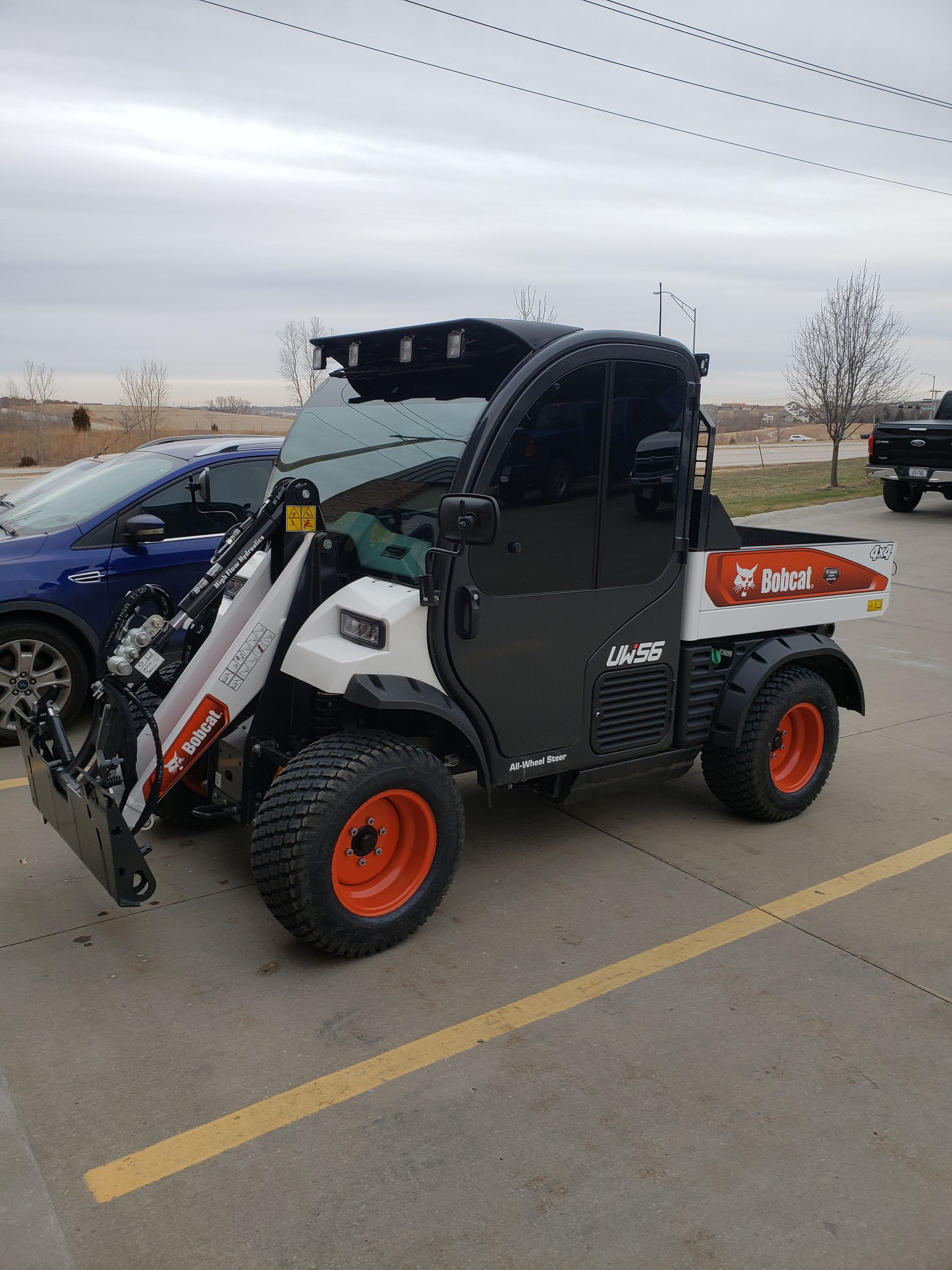 Bobcat Toolcat utility vehicle with loader and enclosed cab, parked in a lot.