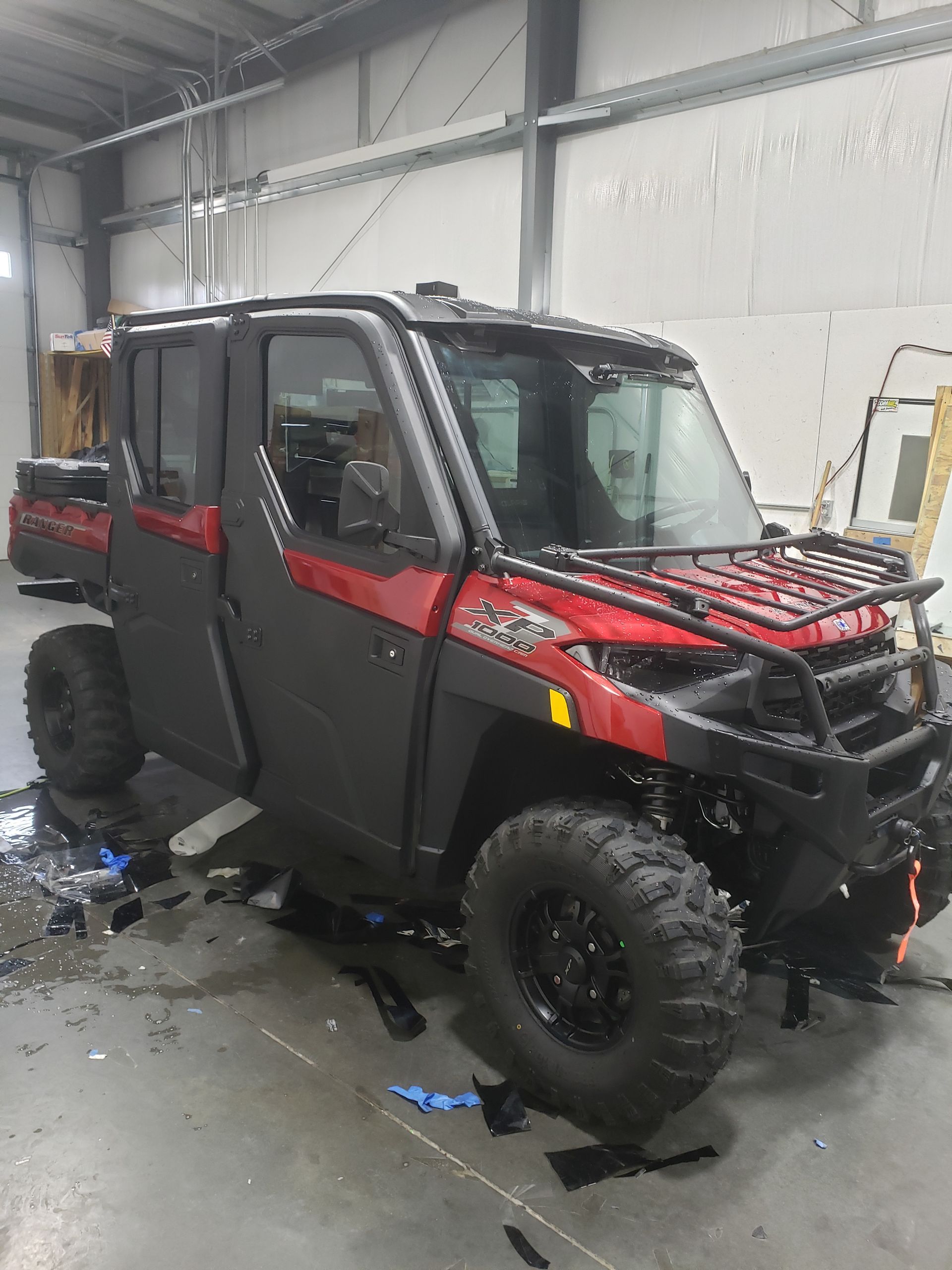 Red and black Polaris Ranger UTV with roll cage and cargo rack in a warehouse.