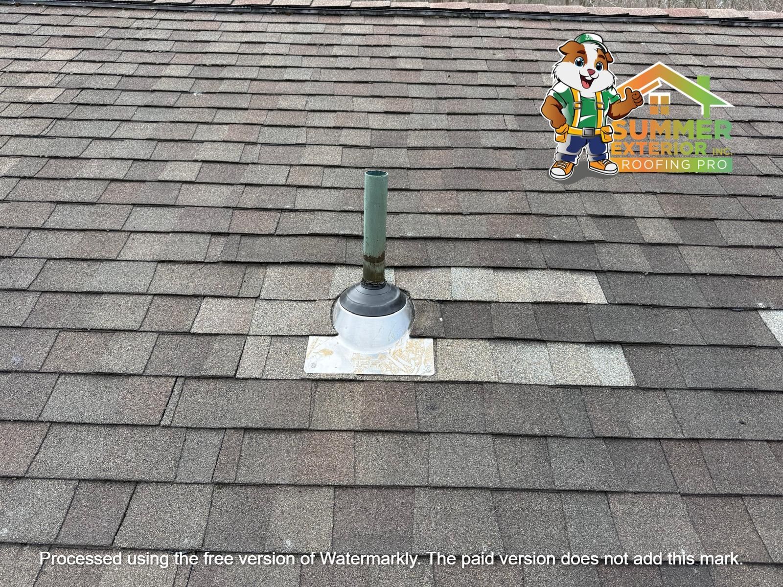 A roof vent pipe with a metal flashing base installed on a grey shingle roof, with a cartoon mascot in the top corner.