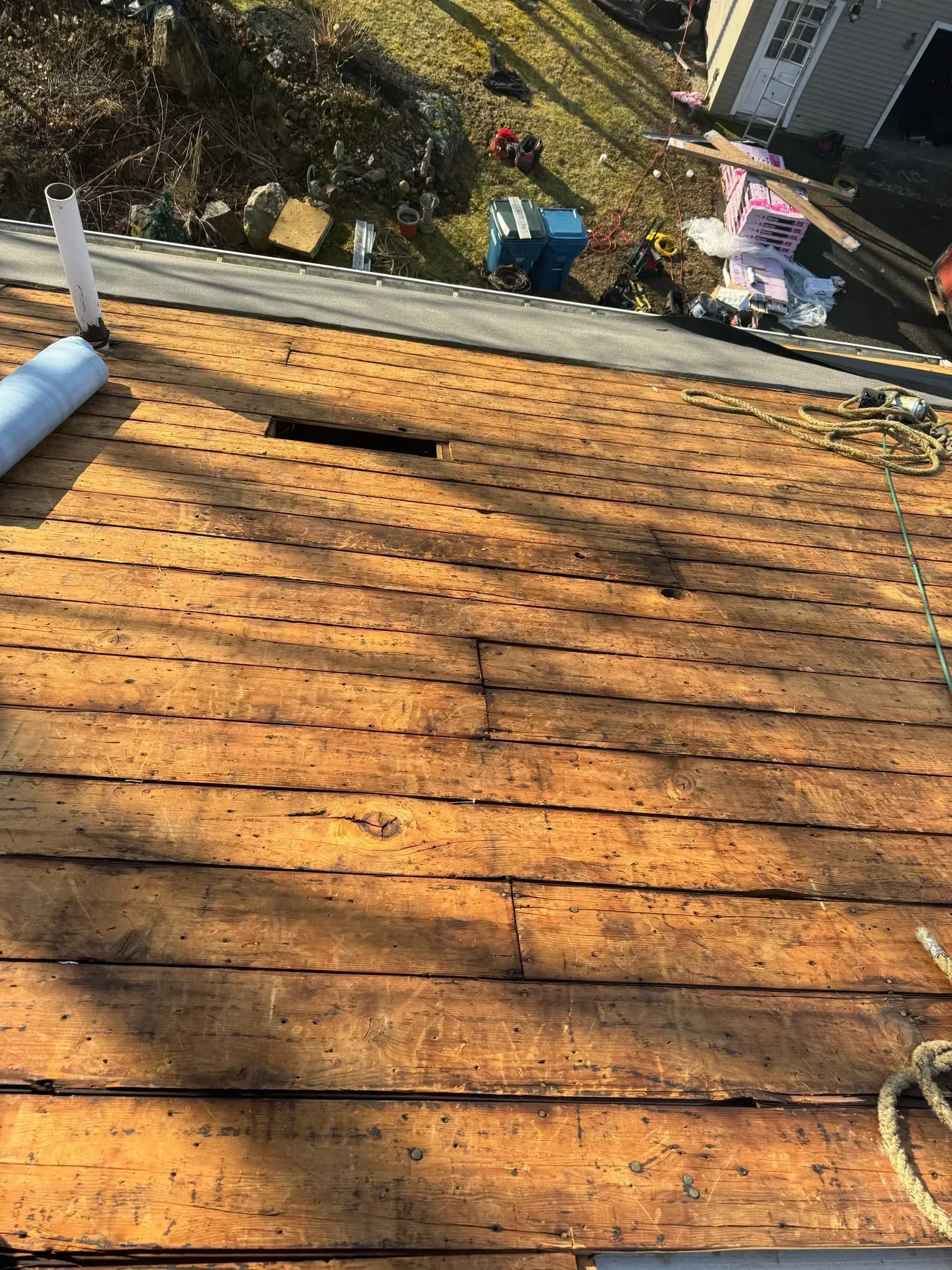 Wood roof with many small holes and a dark patch being worked on.