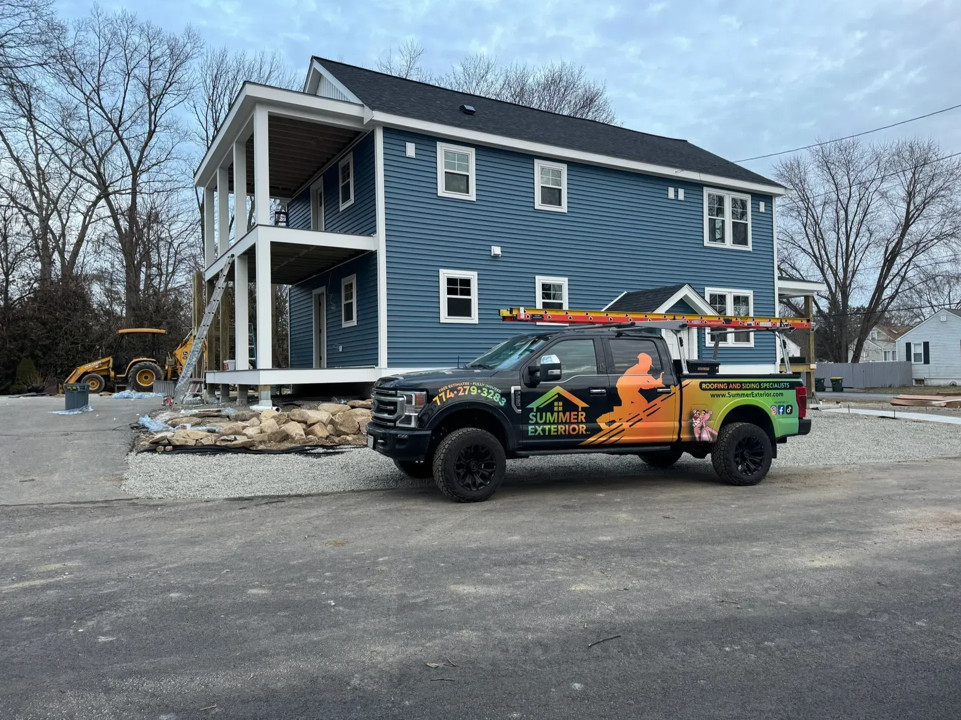 A blue house under construction with a construction truck parked in front.