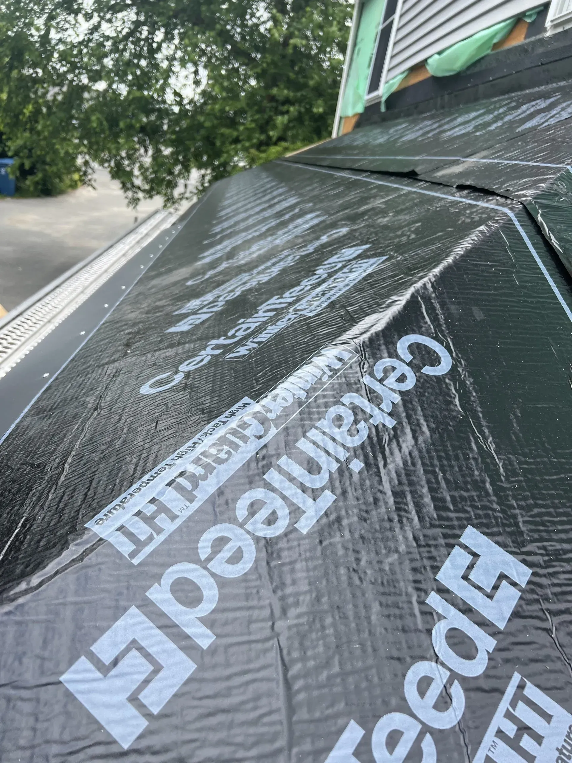 Black CertainTeed roofing underlayment on a roof, with the brand name visible.