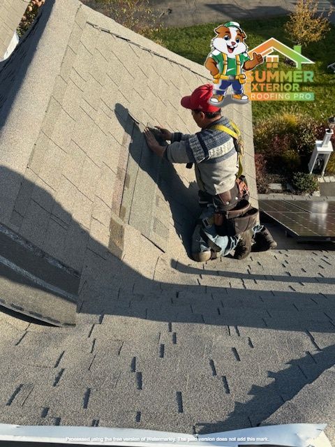 Roofer in safety gear installing shingles on a roof under sunny conditions.