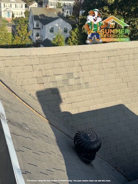 Roof with repaired shingles, a ventilation turbine, and a cartoon mascot in background.