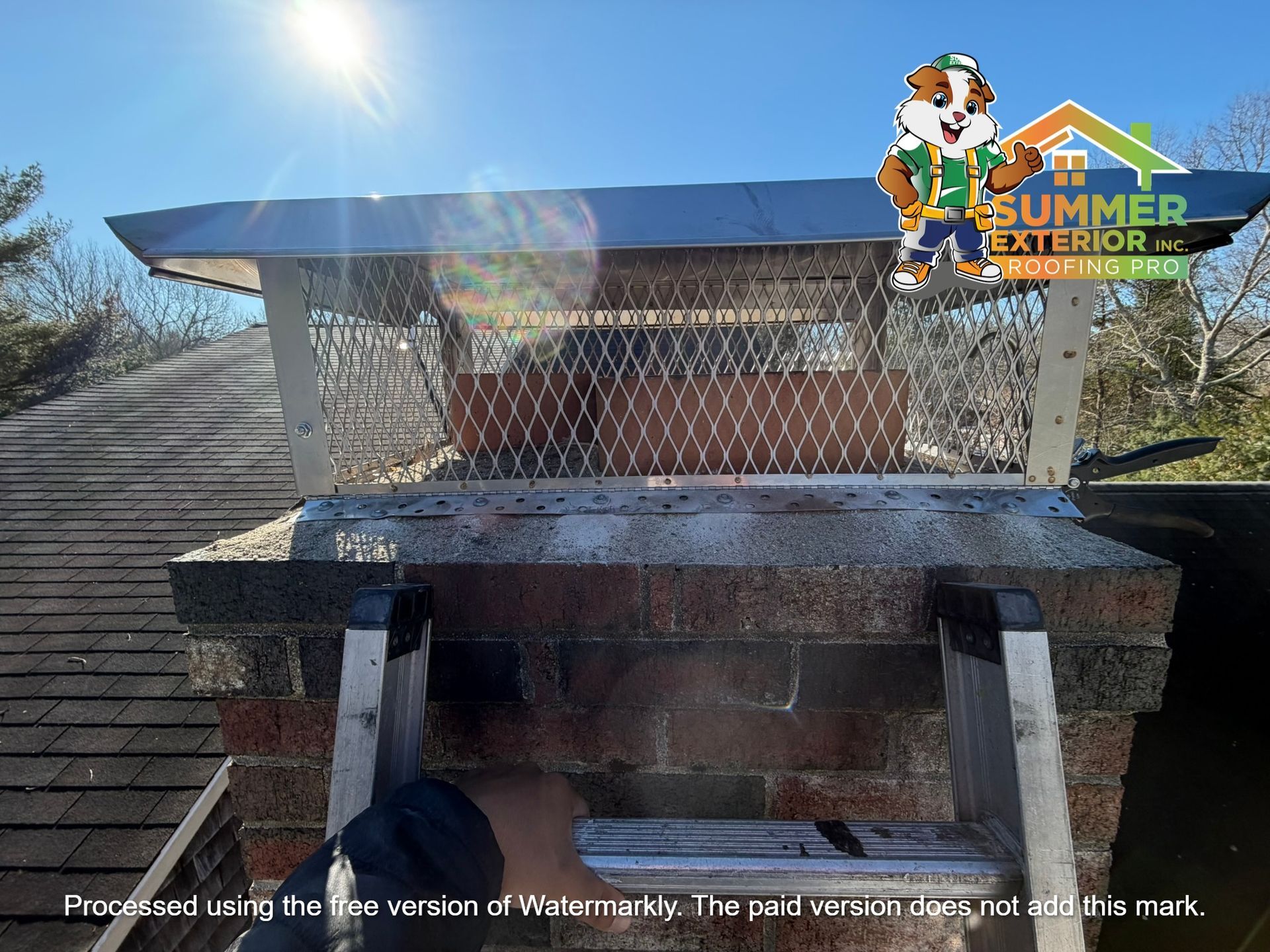 A ladder leans against a brick chimney topped with a metal screen and cap on a sunny roof, with a company logo overlaid.