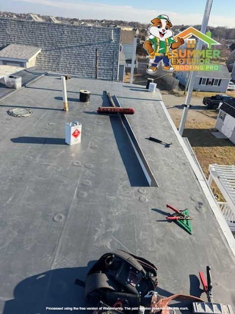 Rooftop with tools and materials, a contractor logo in the sky. Gray roofing, blue sky.