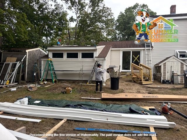 Backyard with house renovation in progress. Siding, tools, ladder, lumber, and people visible.