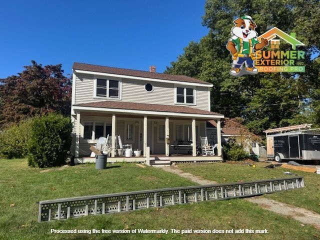Two-story house with beige siding, brown roof, and porch. Ladder in foreground, with a logo in the corner.