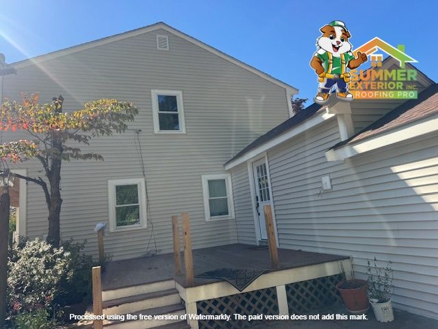 A two-story house with a wooden deck. The house has beige siding and windows.