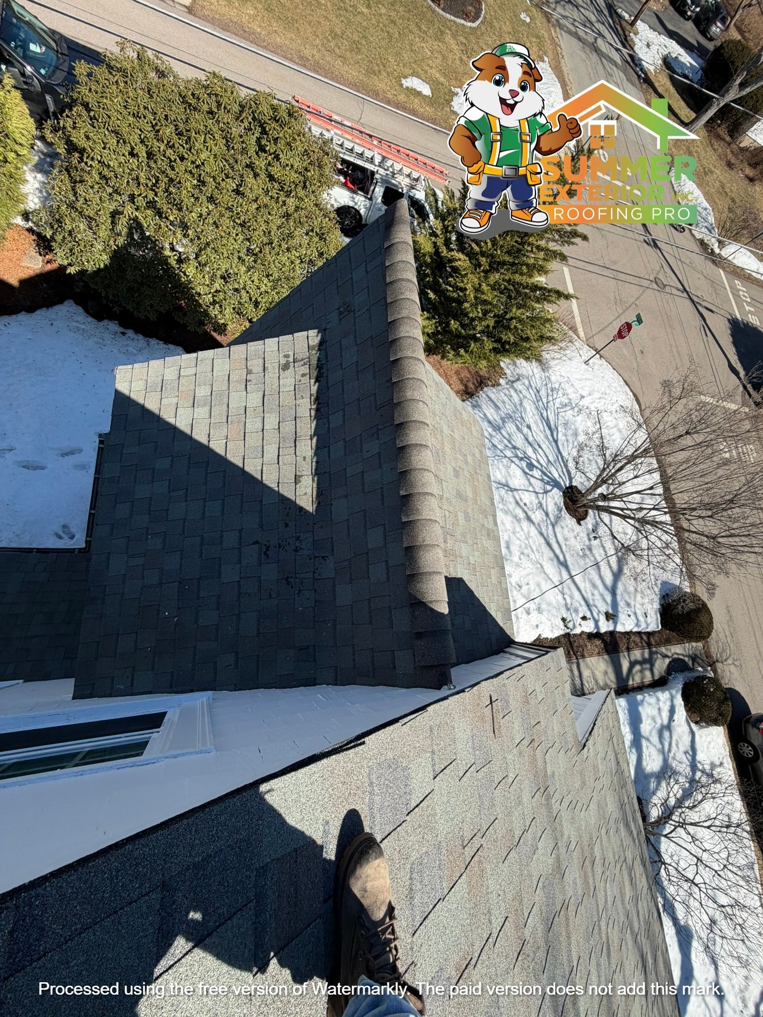 A view from a high-angle perspective looking down a roof ridge toward the ground, showing shingles and a boot.