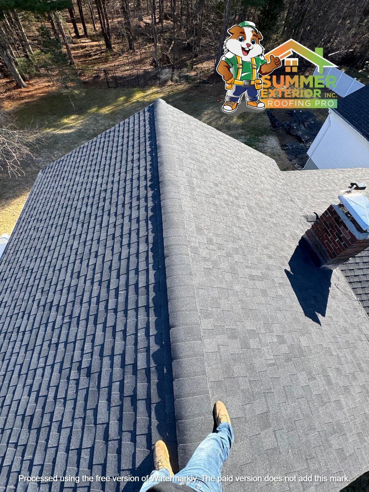 A person stands on a roof showing different shingle colors, with a company logo in the corner.