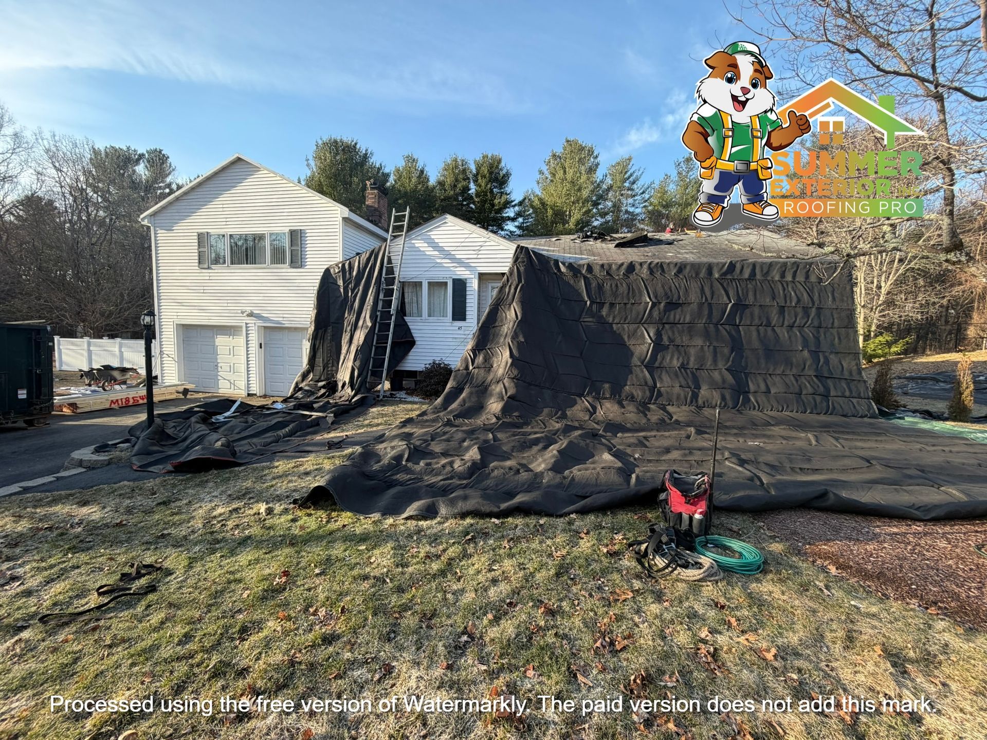 A residential house under roof renovation, draped in black protective tarps, with a cartoon mascot logo in the corner.