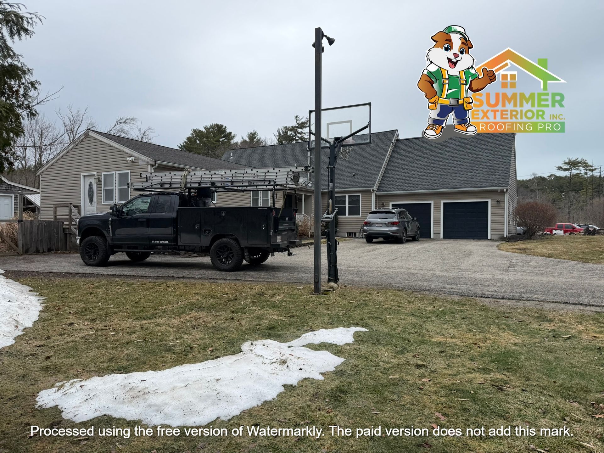 A black utility truck parked in front of a house with a grey roof and an attached garage on a gravel driveway.