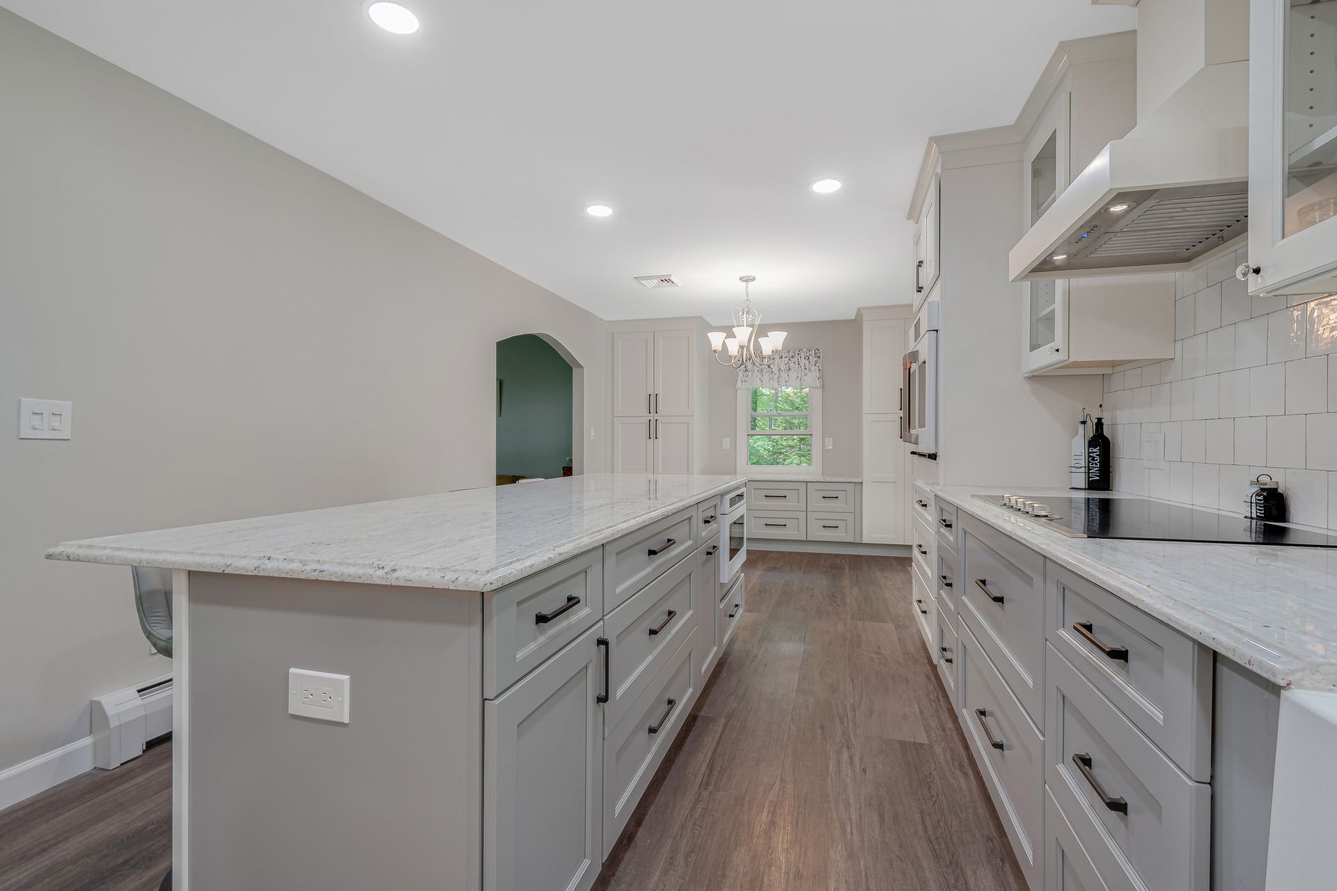 A kitchen with white cabinets, granite counter tops, and a large island