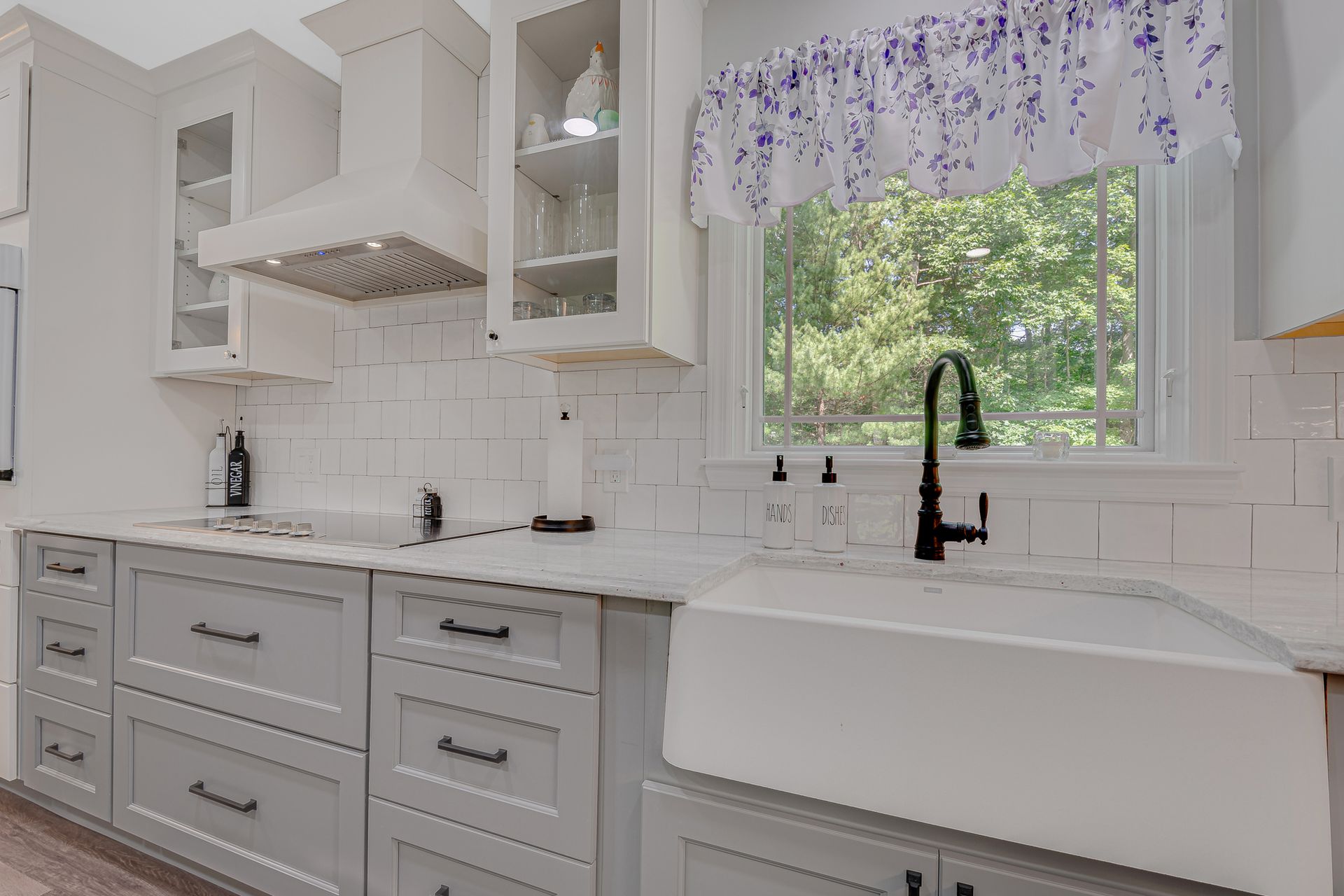 A kitchen with white cabinets and a white farmhouse sink