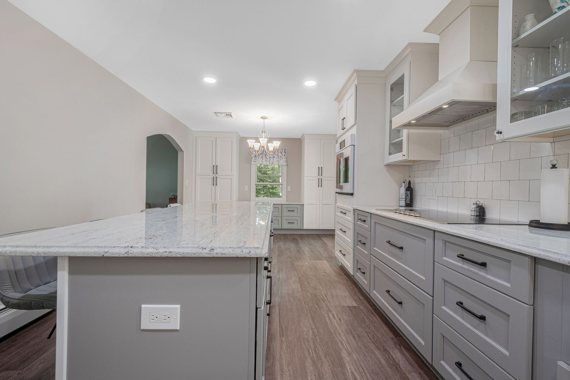 A kitchen with gray cabinets, white counter tops, and a large island