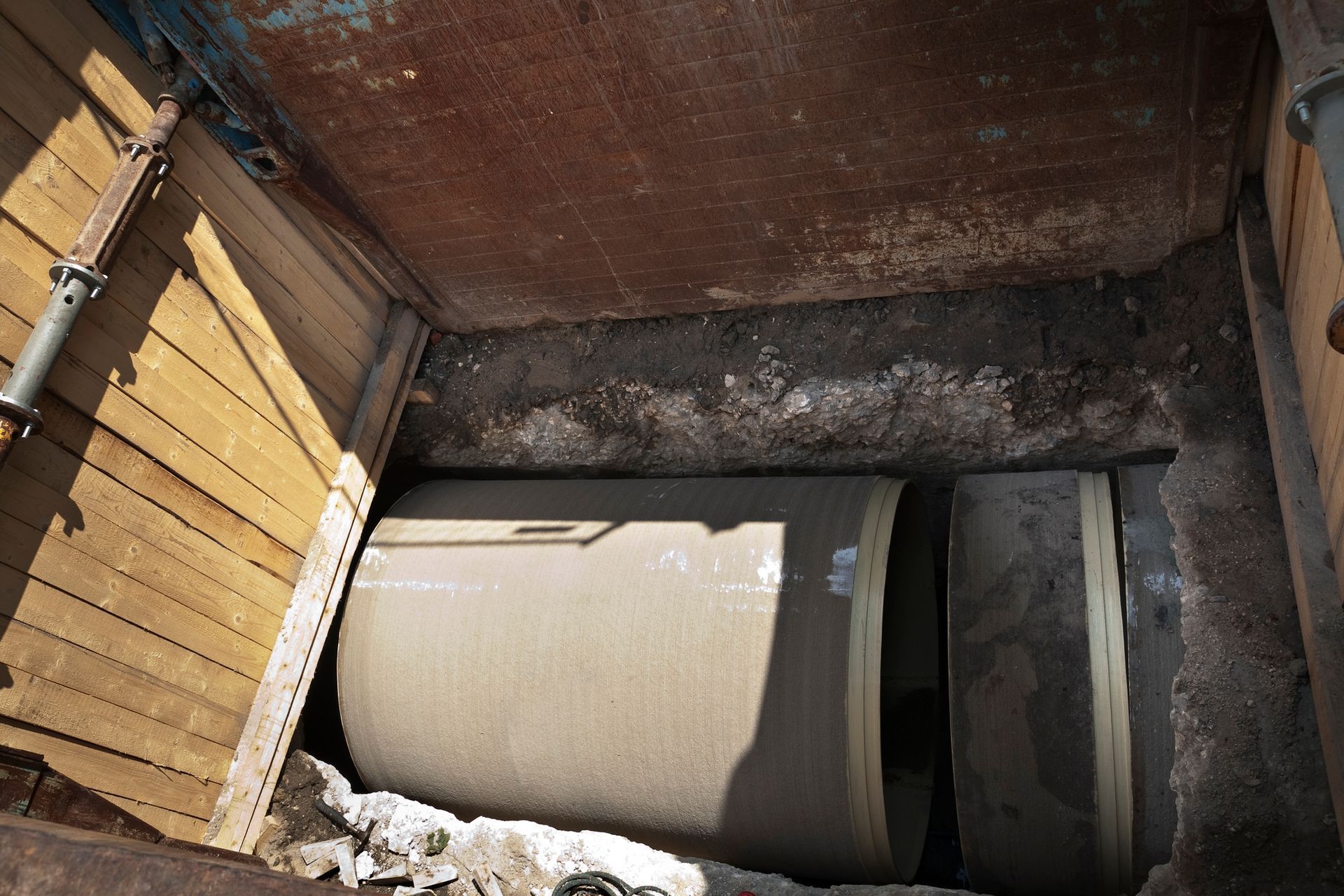 Large concrete cylinders in a trench, inside a wooden support structure.