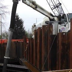 Construction site with a concrete pump pouring into a metal retaining wall.